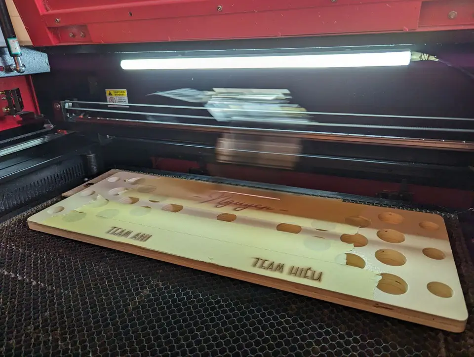 A CNC laser cutter engraving a wooden beer-pong board
