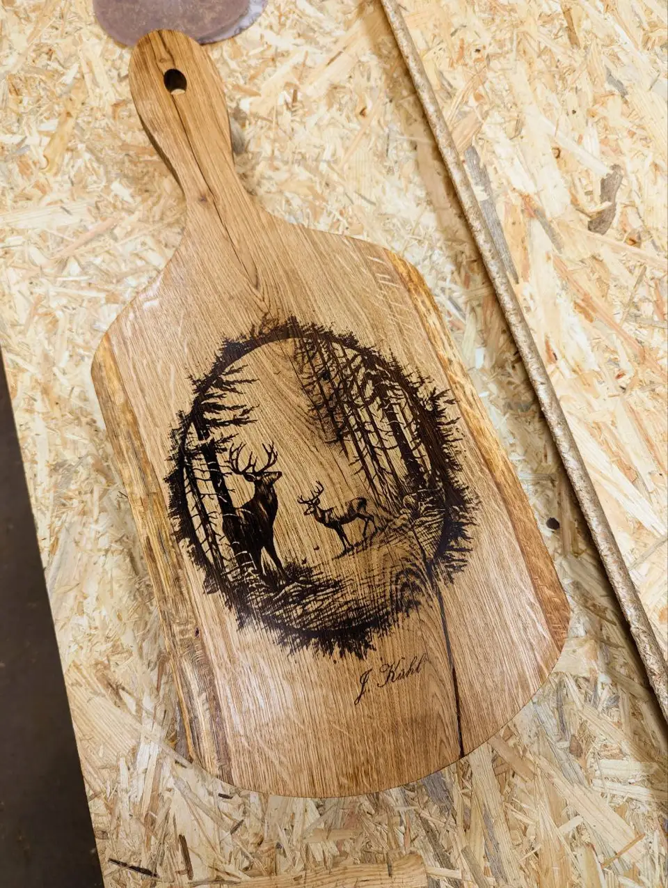A wooden cutting board engraved with deer in a forest