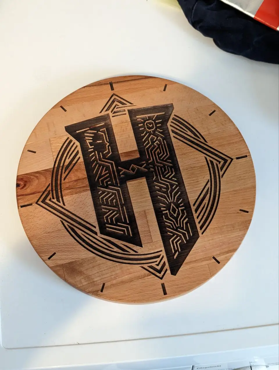 A round wooden clock face engraved with the Hytale letter H