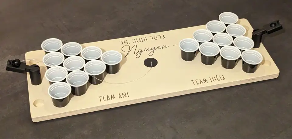 A personalized wooden miniature beer-pong board with black cups